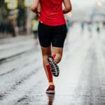 Woman running in the rain | Featured image for calf injuries article.