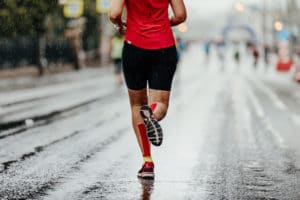 Woman running in the rain | Featured image for calf injuries article.