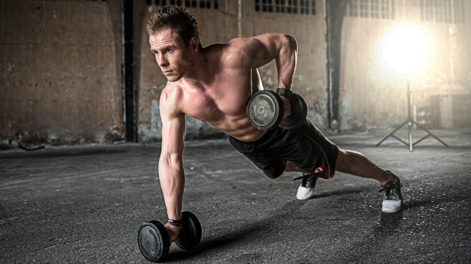 Bare chested male using weights | Featured image for The Importance of the Trunk blog for Pivotal Motion Physiotherapy.