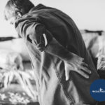 Man in pain holding his back | Featured image for 5 Tips for Getting Better Sleep with Night Pain blog for Pivotal Motion Physiotherapy.