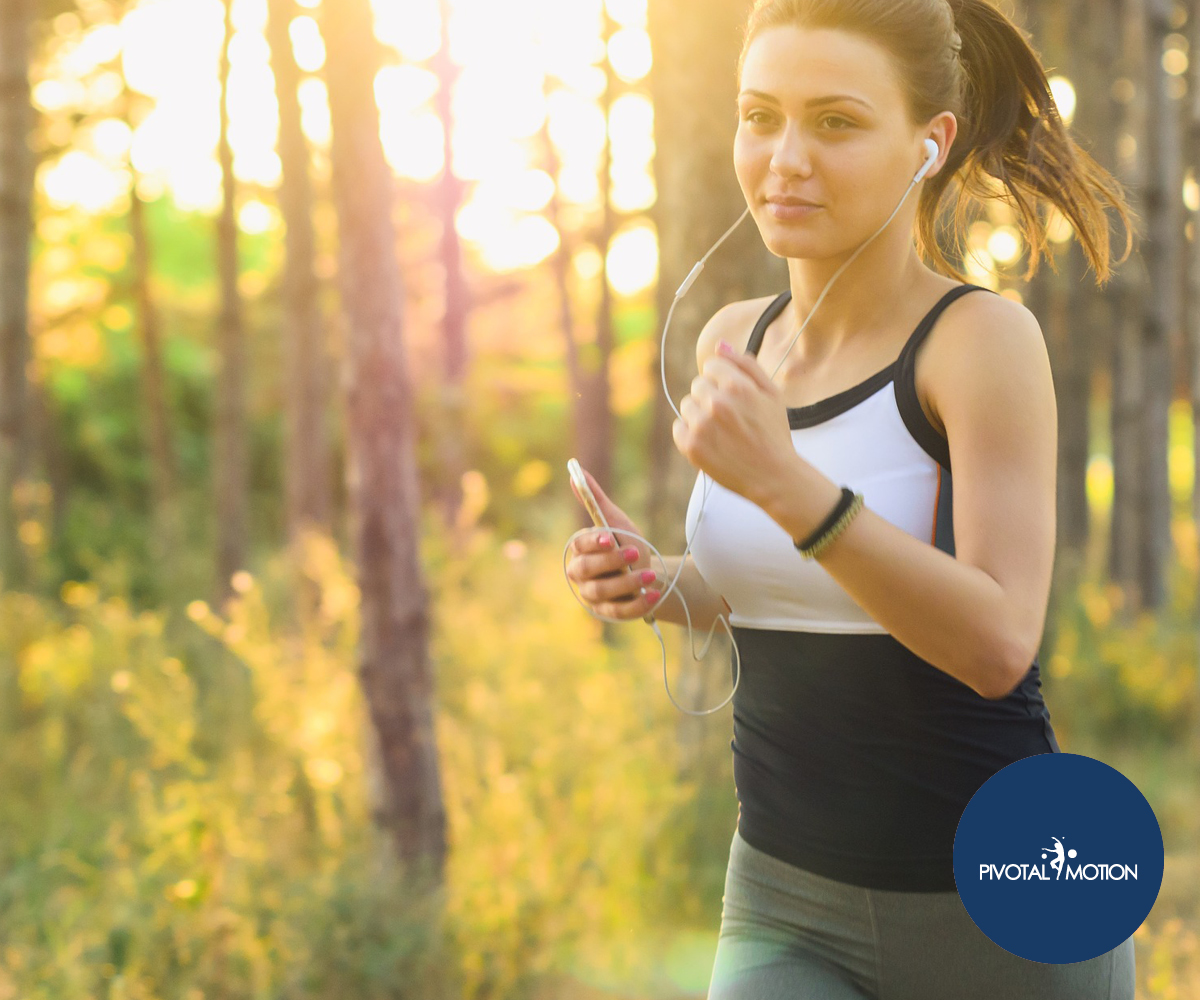 Woman running in a forest | Featured image for Why Trail Running is a Workout in Itself blog for Pivotal Motion Physiotherapy.