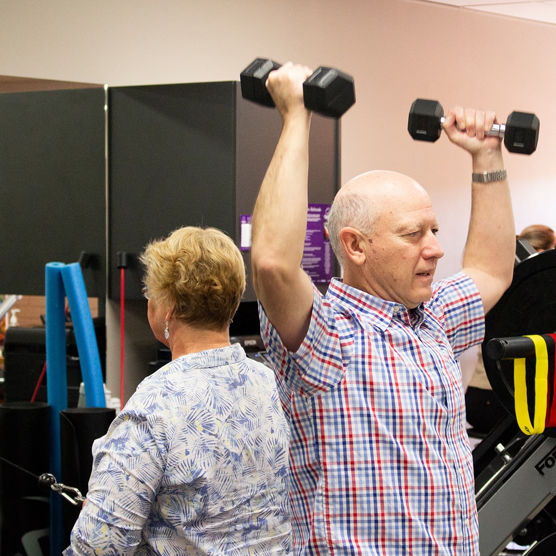 Elderly man lifting two dumbells.