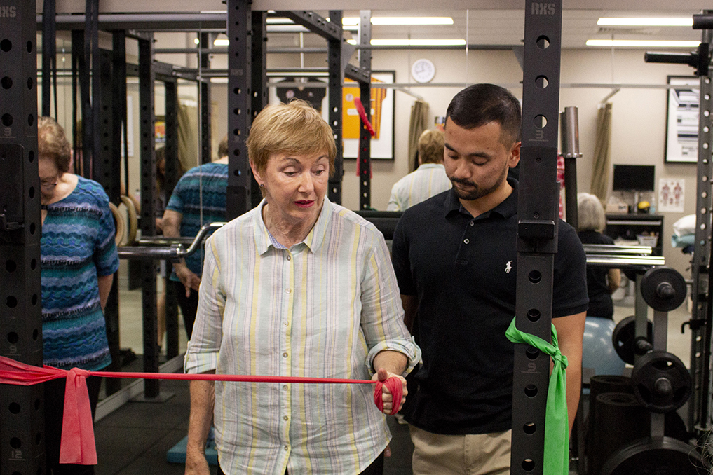 Woman and trainer practicing shoulder warm up exercises | Featured image for Shoulder Warm Up Exercises blog for Pivotal Motion Physiotherapy.