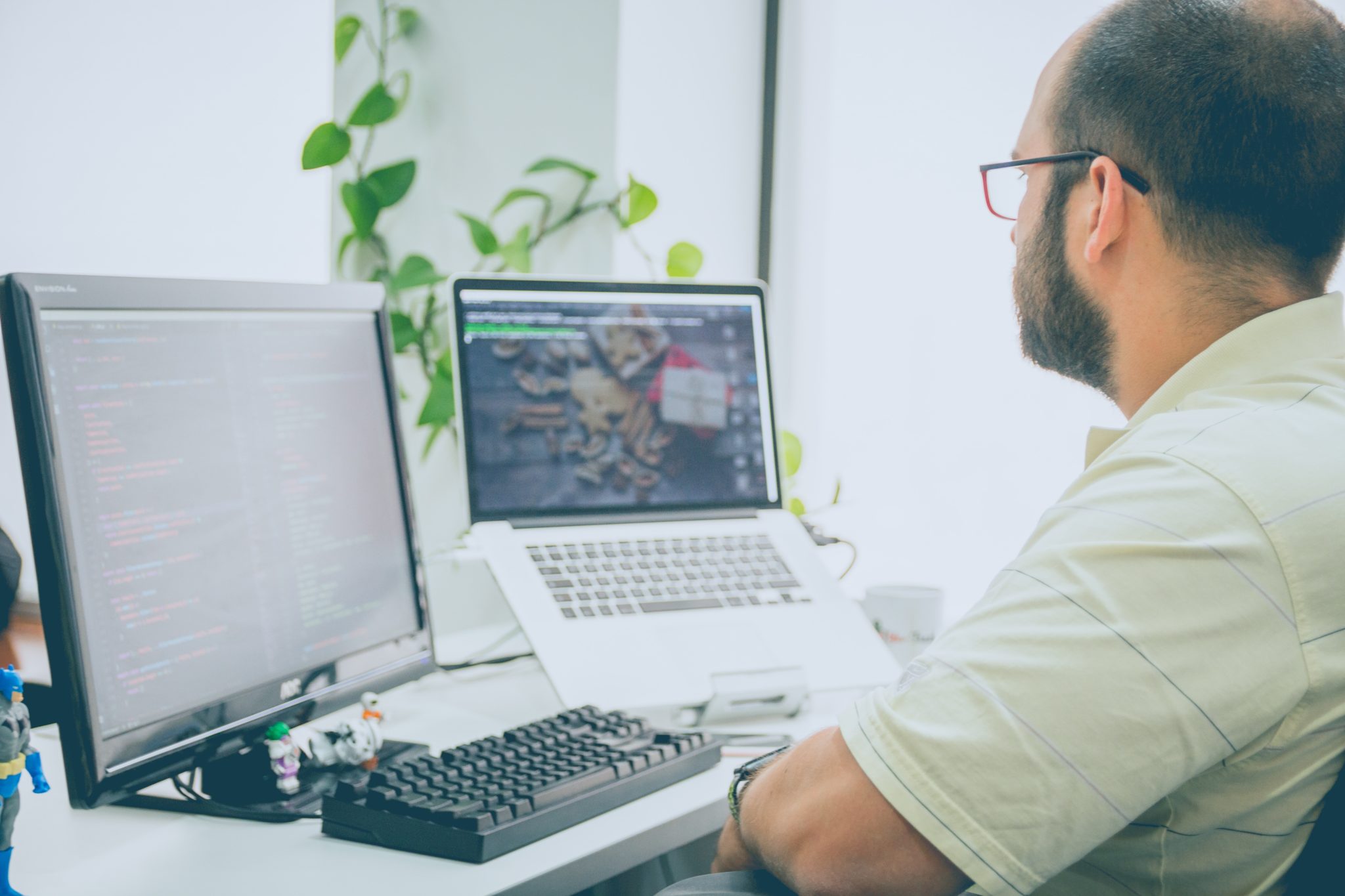 Male office worker at desk using two computers.