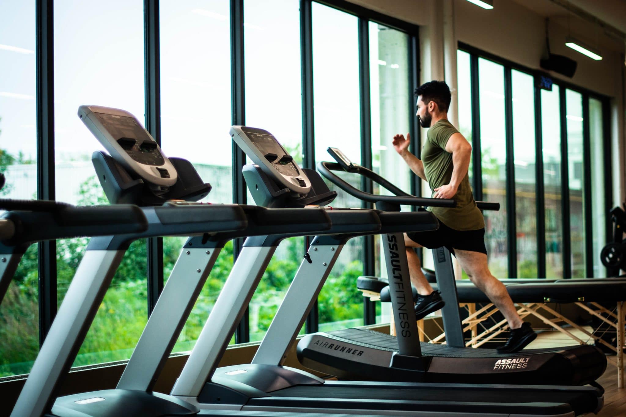 Man running on machine in front of windows