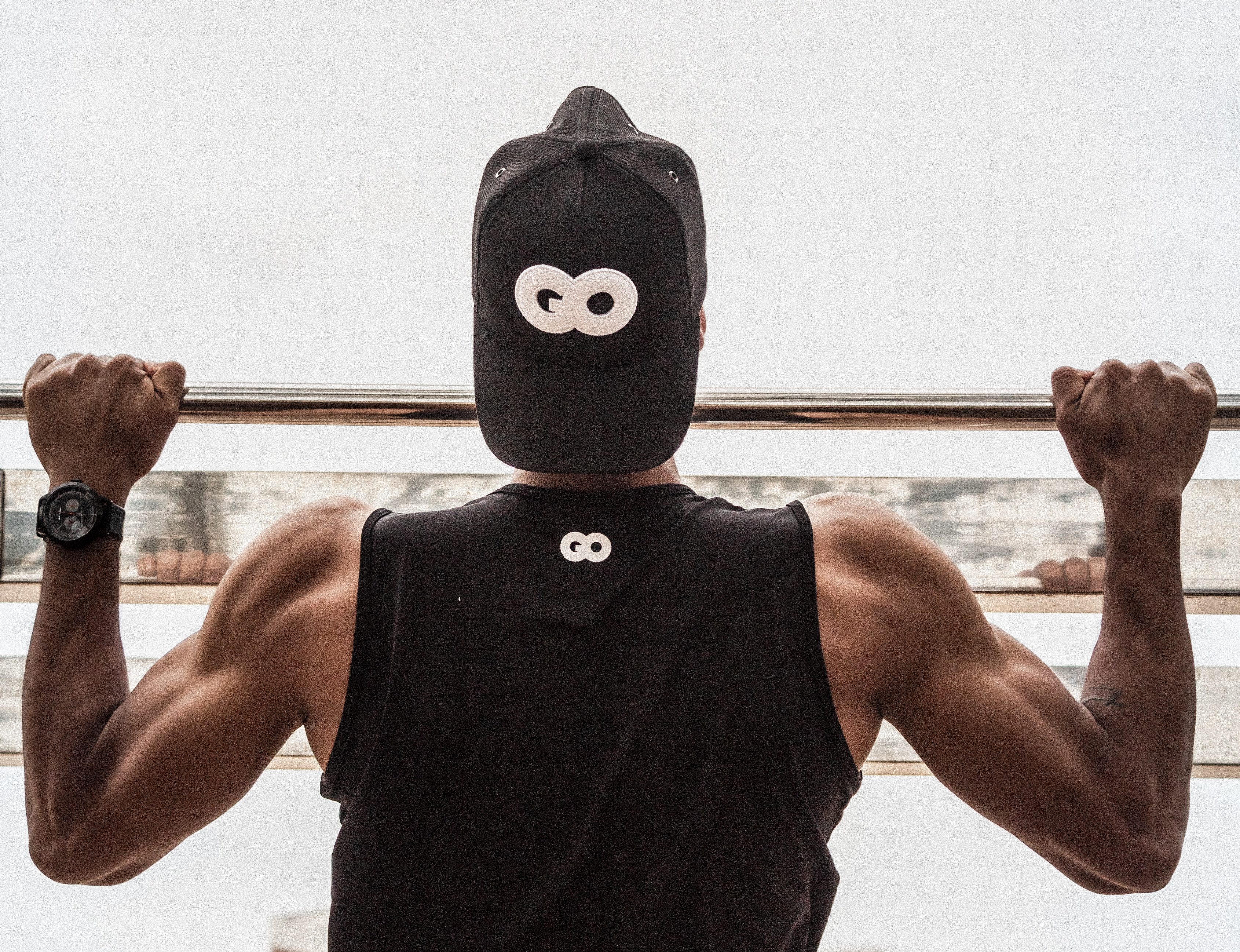 Man doing pullups wearing Go cap.