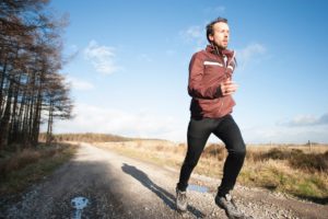 Man exercising in winter on gravel track.