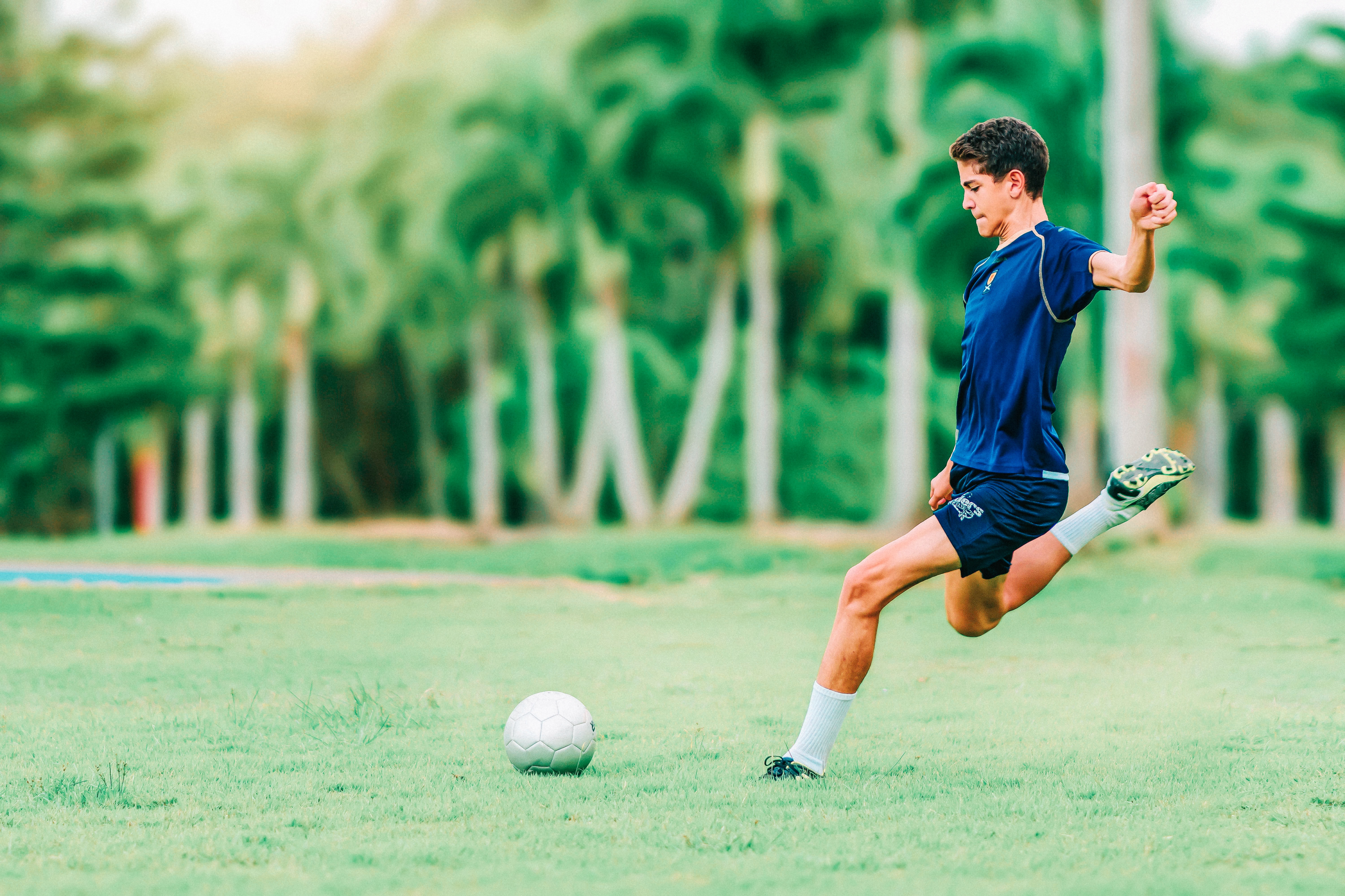 Boy playing soccer in green field.