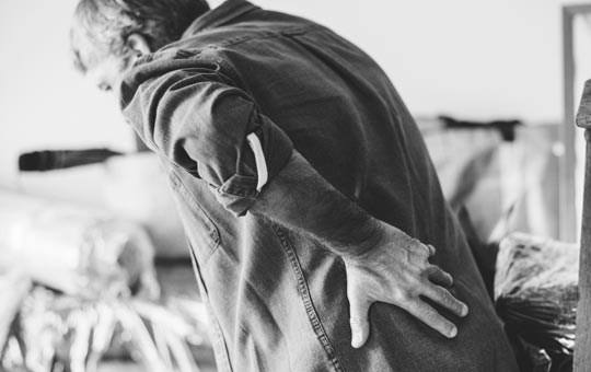 Person holding his back in pain | Featured image for the Trunk Muscles and Low Back Pain blog for Pivotal Motion Physiotherapy.