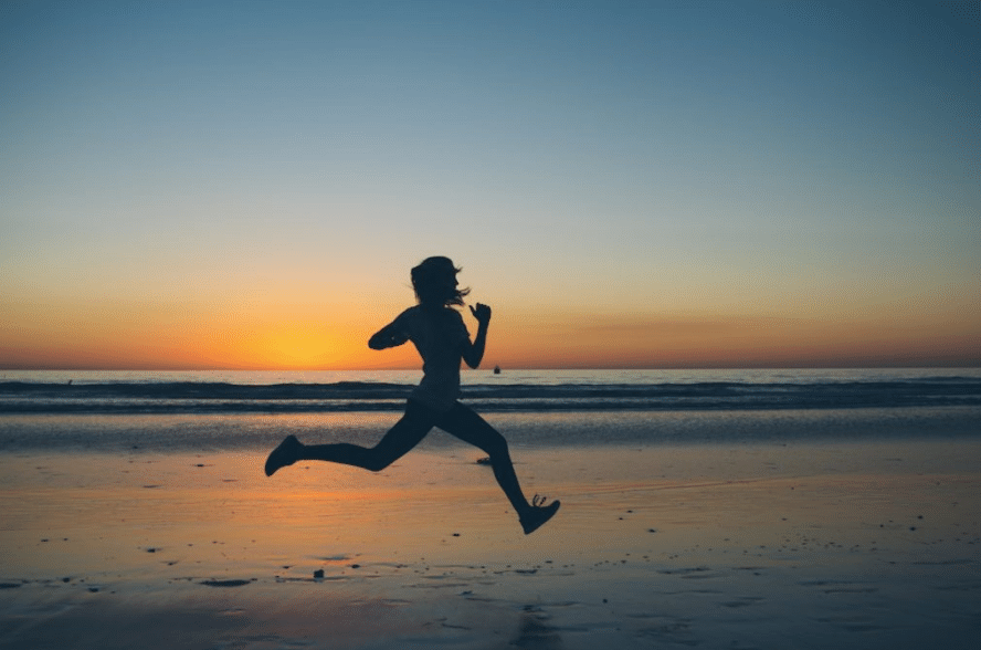 Person sprinting down a sunset beach.