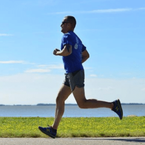 man running down grassy waterfront