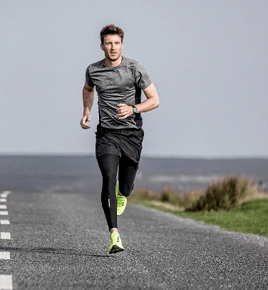 Man running down an asphalt road | Featured image for stress fractures blog.