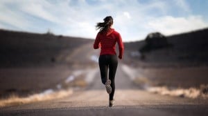 Woman running down a rural road | Featured image for running load management blog.