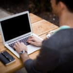 What causes chronic pain - Blog featured image showing a person working on their laptop, sitting with their back straight