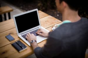 What causes chronic pain - Blog featured image showing a person working on their laptop, sitting with their back straight