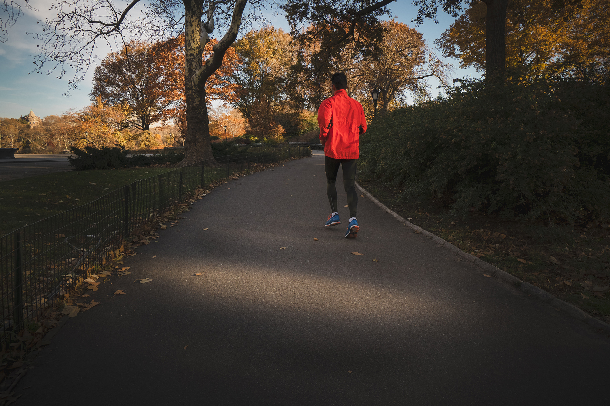 Man with red shirt running along a concrete footpath