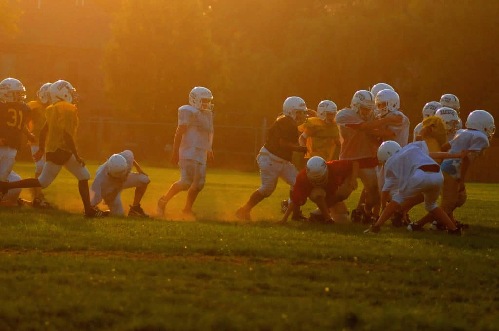 Concussion prevention blog featured image showing a team of American Football playing children wearing protective gear