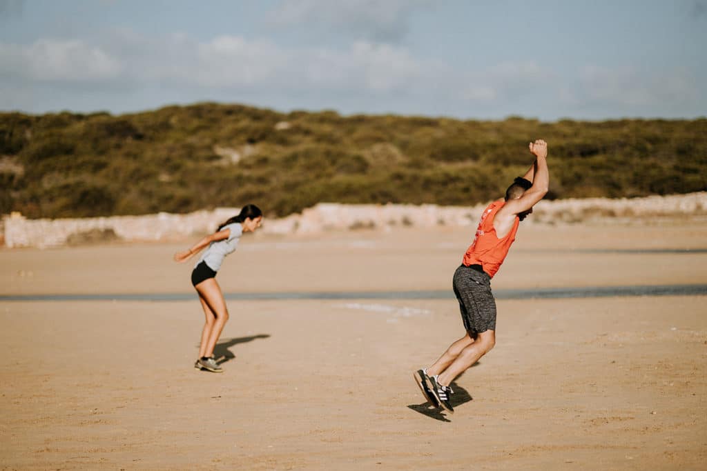 Two people exercise on the beach | Featured image for ACL Management blog.