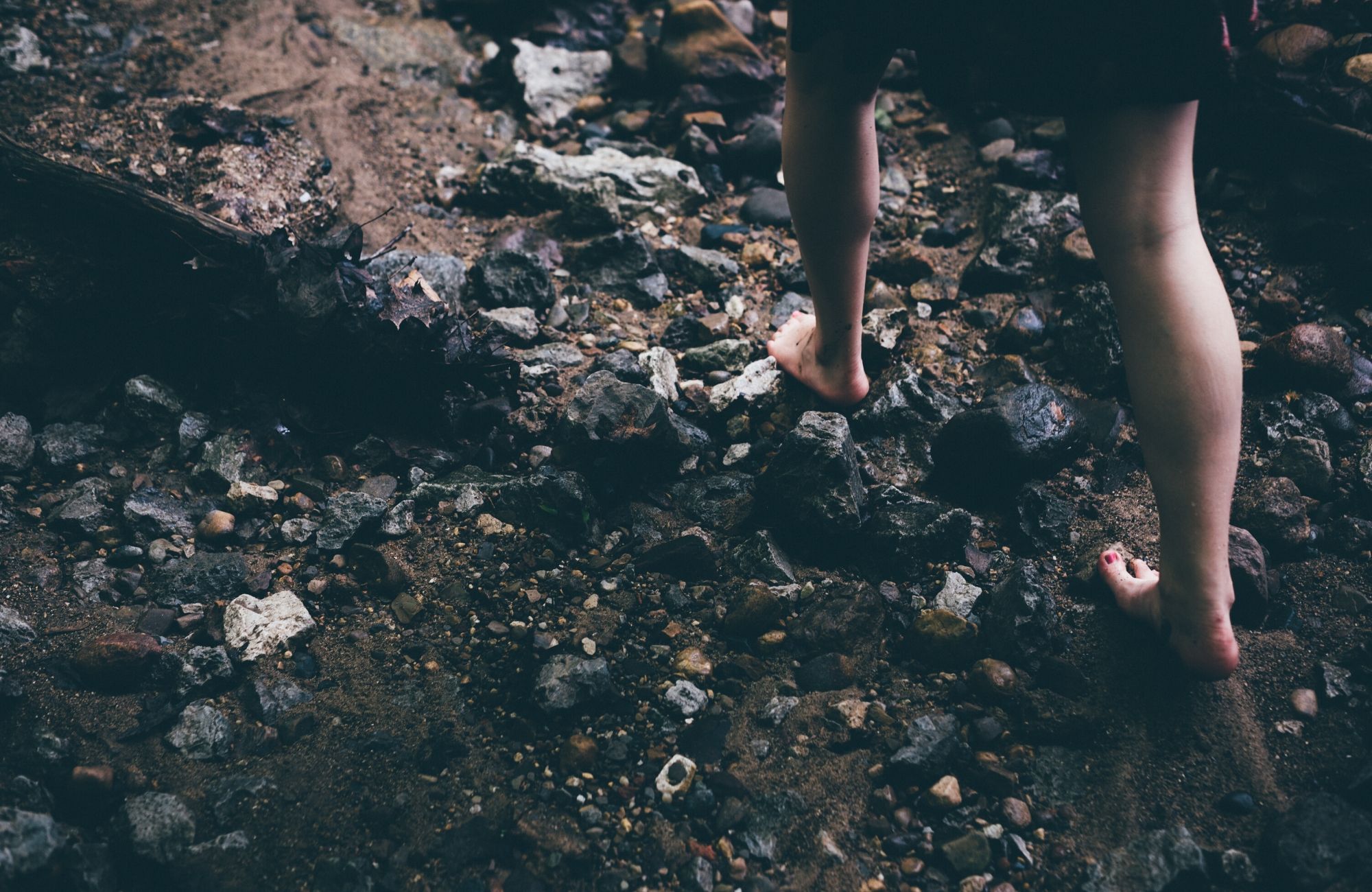 A barefoot person traversing rough terrain