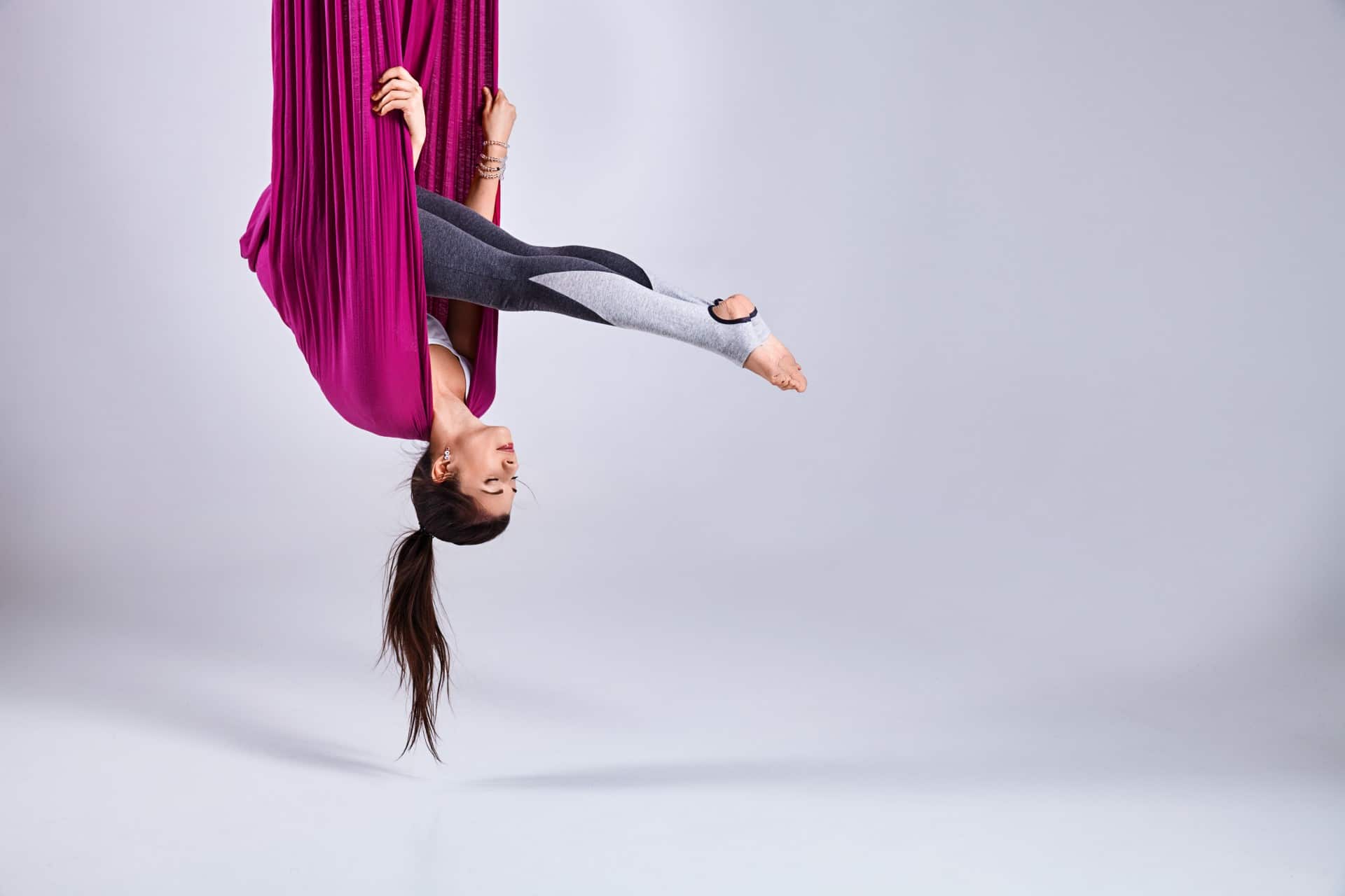 Acrobat hanging upside down in cloth.