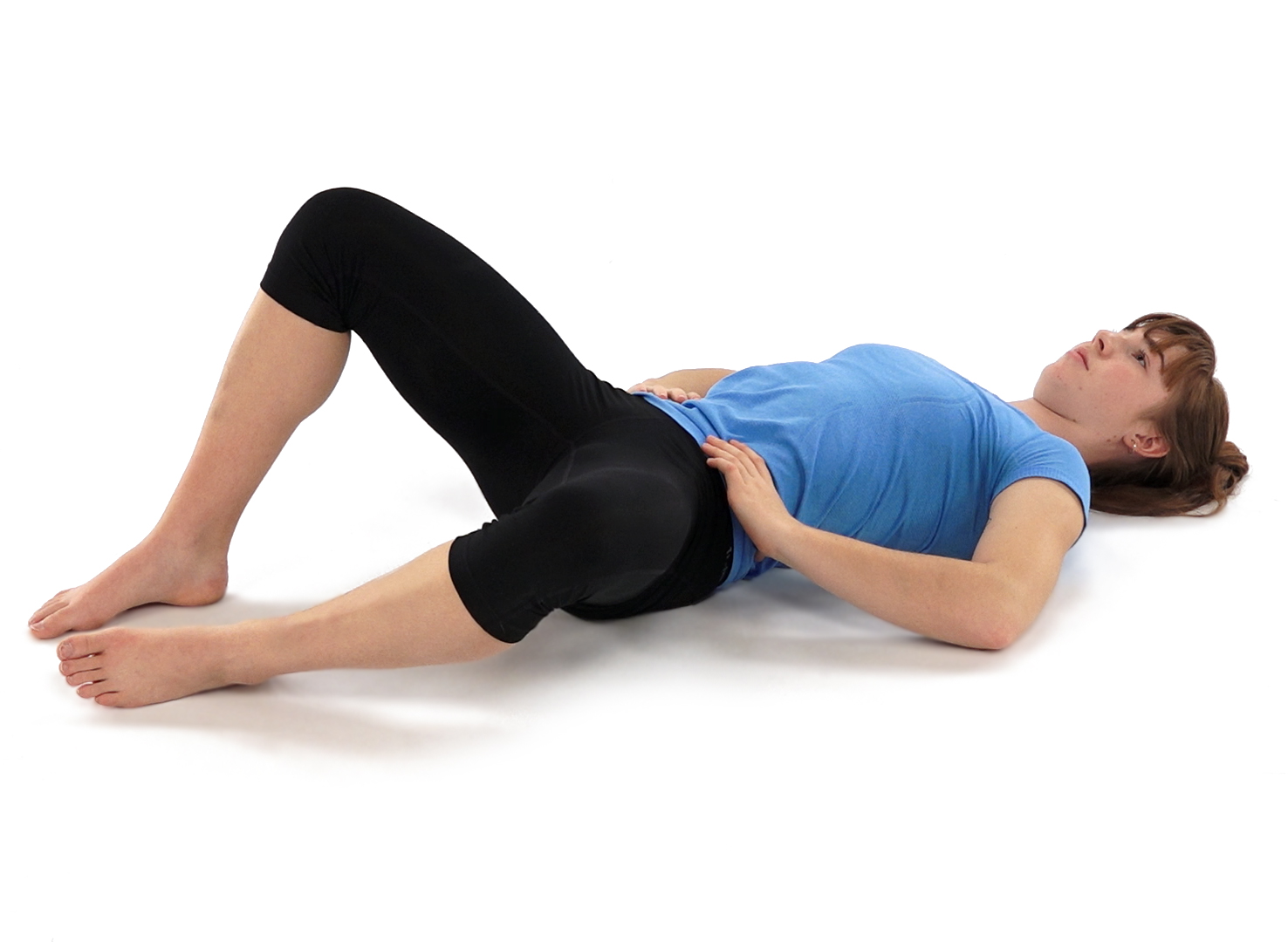 Woman with blue shirt and black pants stretching on floor