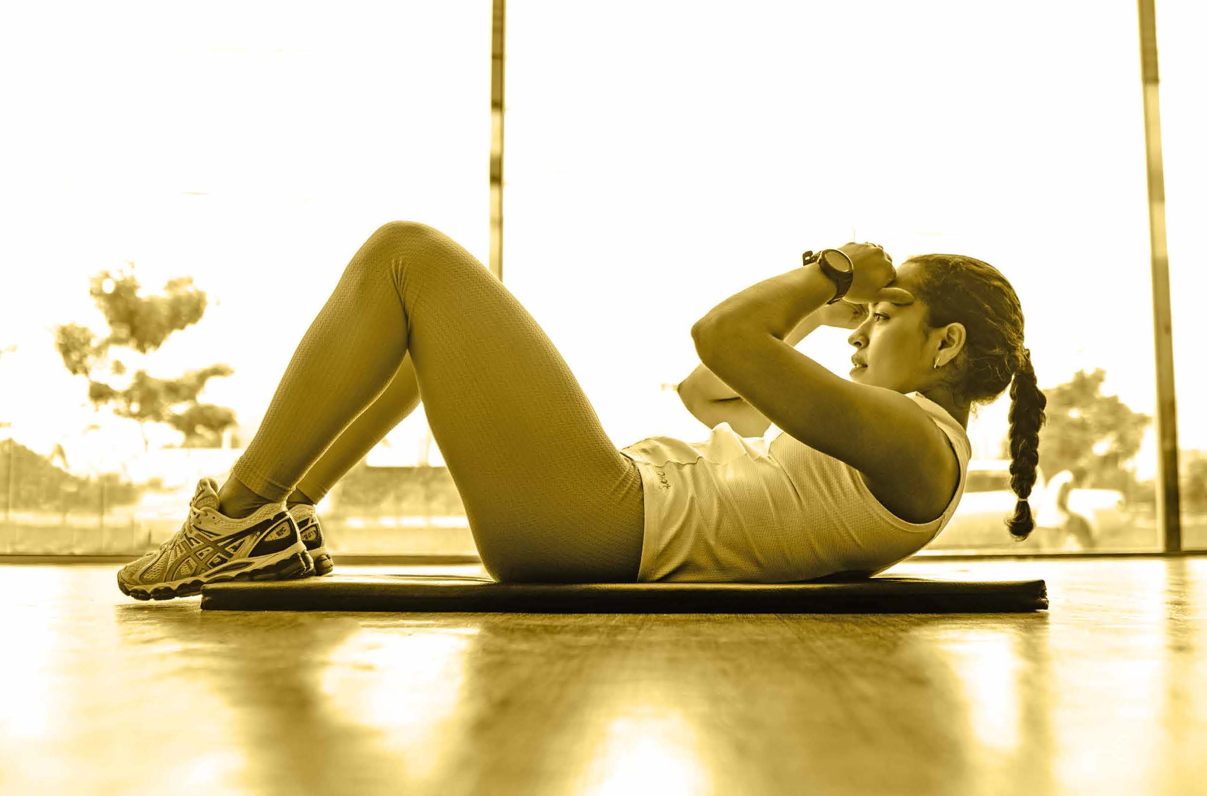Image of woman doing sit ups on an exercise mat | Featured image for Exercise and Academic Performance blog for Pivotal Motion Physiotherapy.