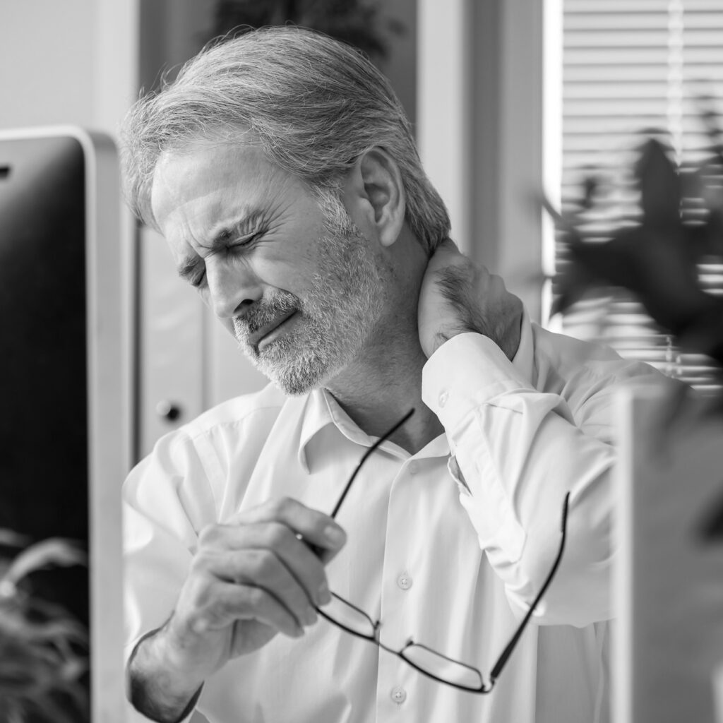 Tired businessman working in his office rubbing neck