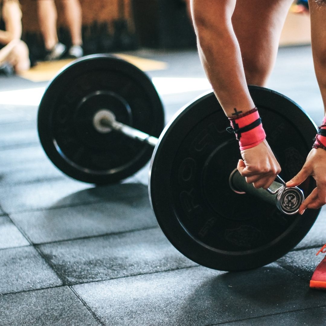 Guy adjusting the weights on a barbell | featured image for Balancing training load and life load.