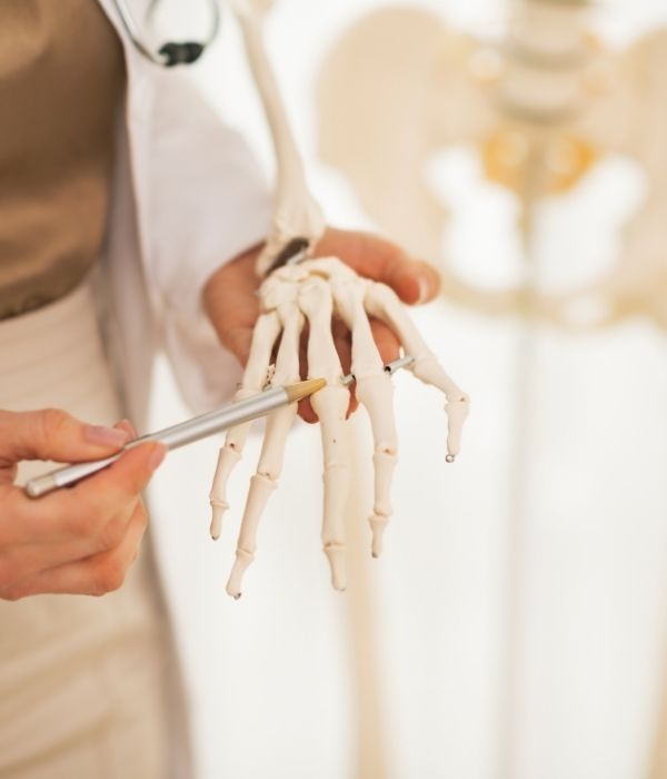 Doctor indicating knuckles on the fingers of a skeleton | featured image for The Sporting Hand.