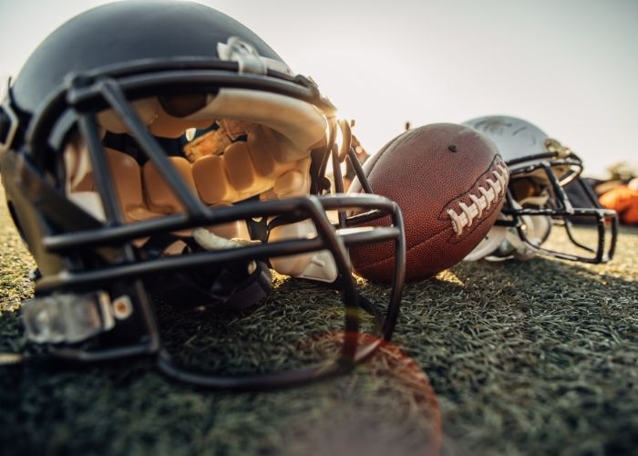 A close up of two football helmets and a football | Featured image on Concussion.