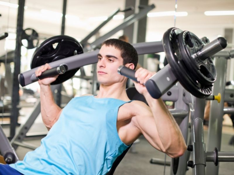 A close up of a man using gym equipment | Featured image on Pectoralis Major Muscle Strains.