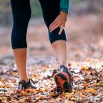 A person who is outside with their hand on their calf holding a cramp | Featured image on Calf Cramps.