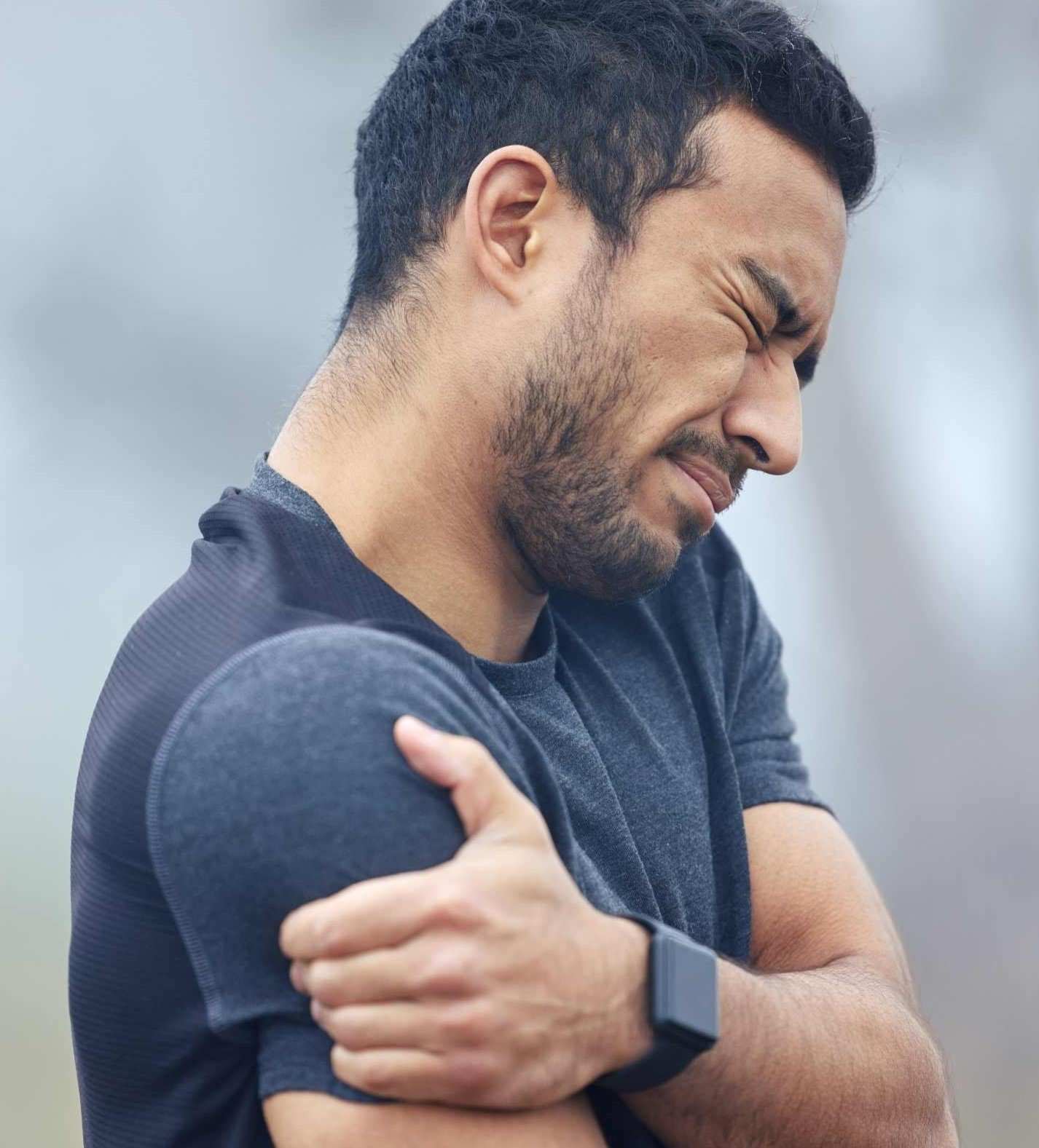 Athletic young man grabbing his shoulder in pain | Featured Image for the Calcific Tendonitis Shoulder Treatment Page of Pivotal Motion Physiotherapy.
