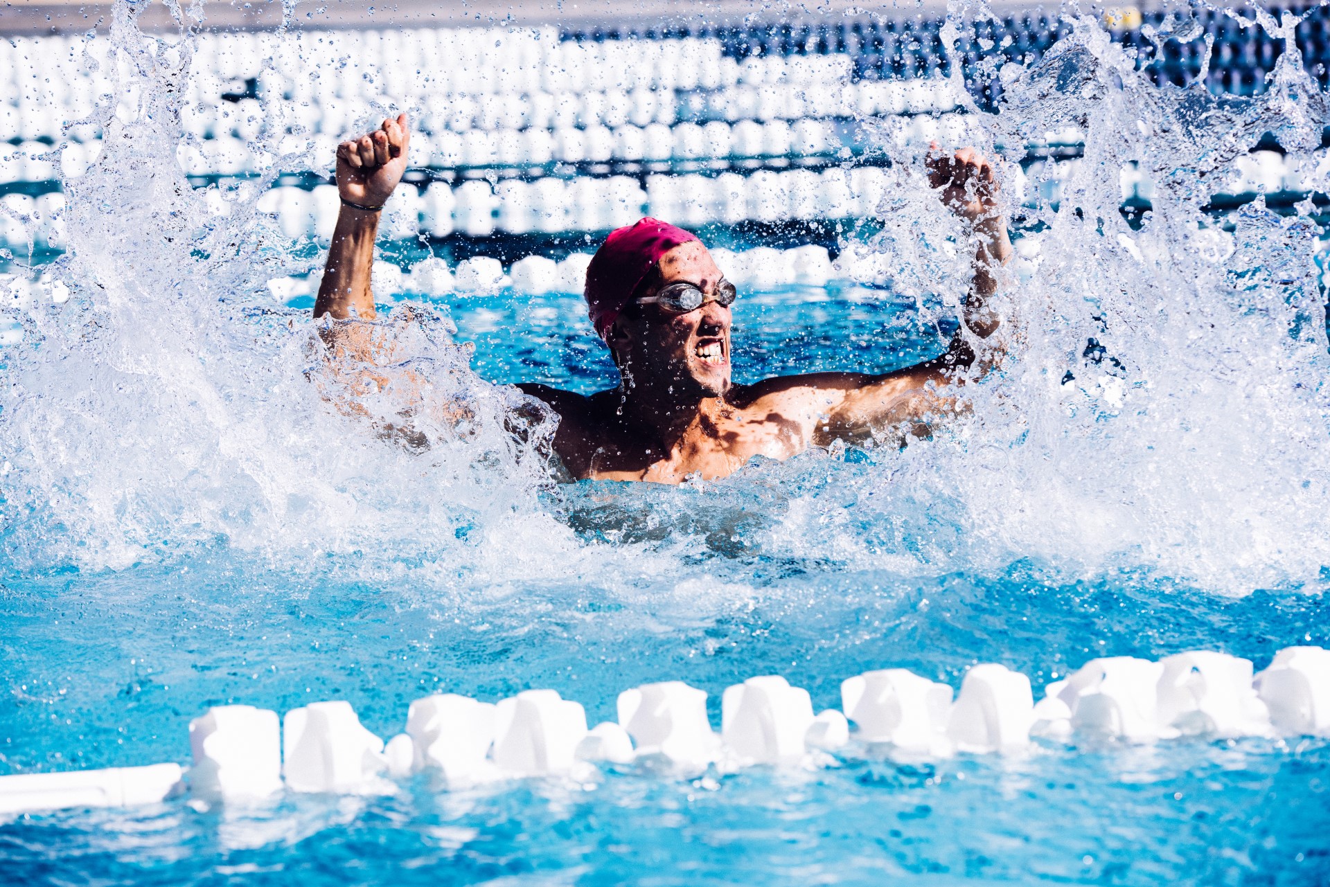 A swimmer in the pool celebrating | Featured image for the Gym Exercises for Swimmers blog from Pivotal Motion Physiotherapy.