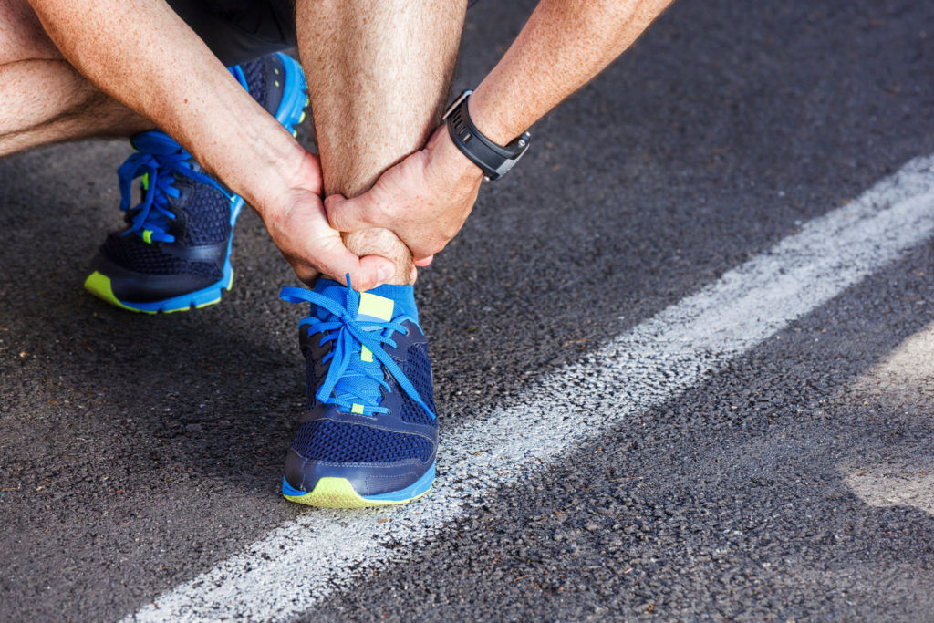 Man clutching their ankle and in need of sprained ankle treatment | Featured image for the Sprained Ankle Treatment page of Pivotal Motion.