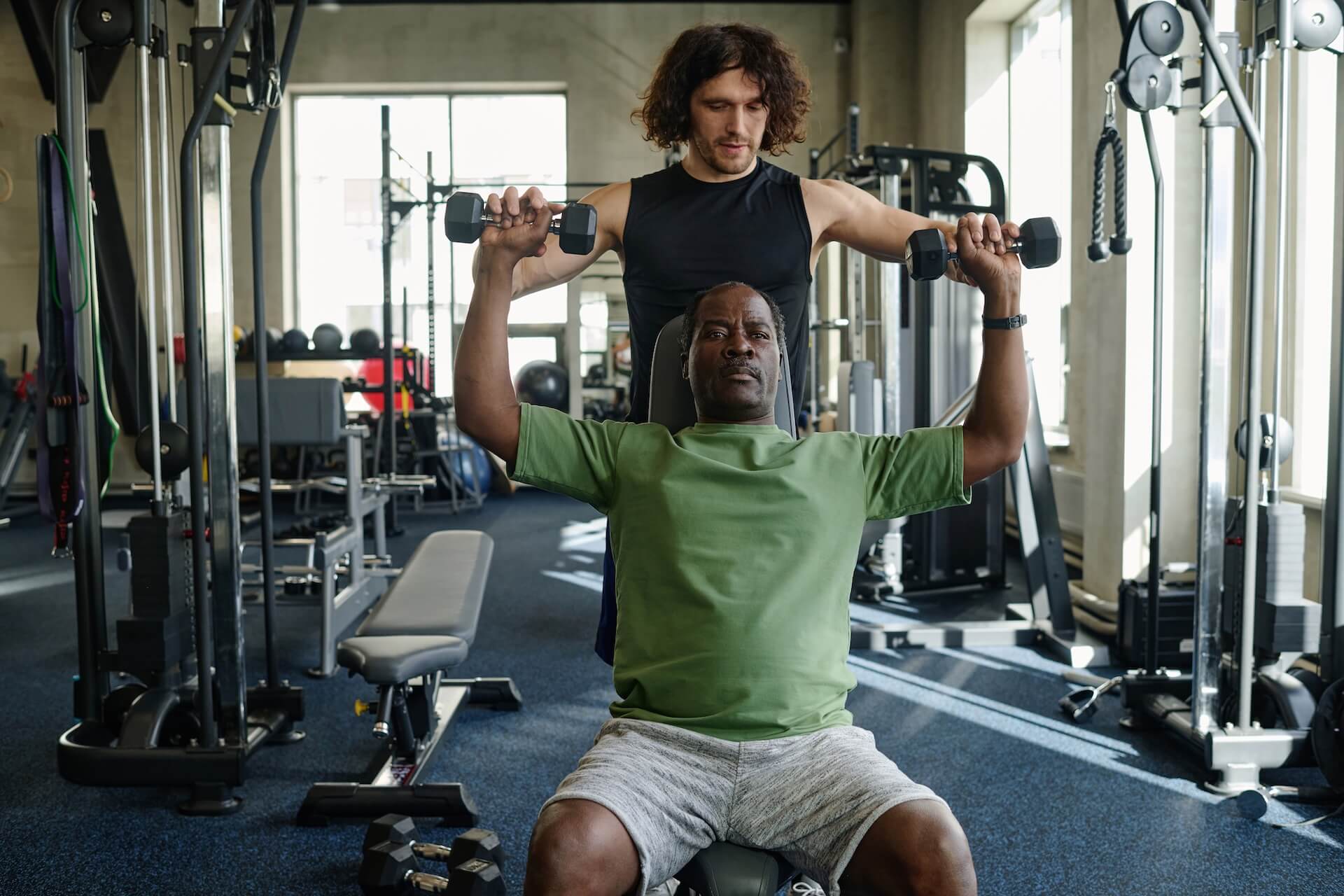 Man taking part in weight lifting classes get assistance from an exercise physiologist | Image for the Weight Lifting Classes service page.